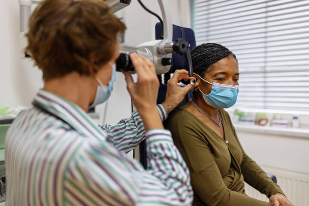 doctor examining the ear of a senior woman in clinic - angiologista - fotografias e filmes do acervo