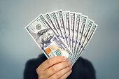 1000 dollars in 100 bills in a man's hand close-up on a dark background. Hands holding dollar cash