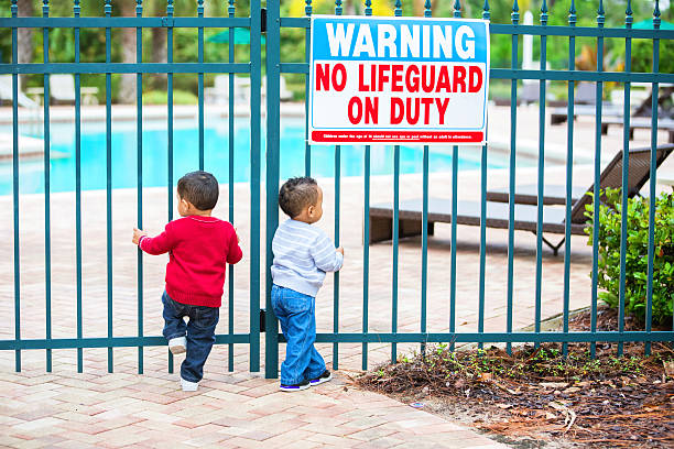 double trouble. twin boys try to get into locked pool - swimming pool gate stock pictures, royalty-free photos & images