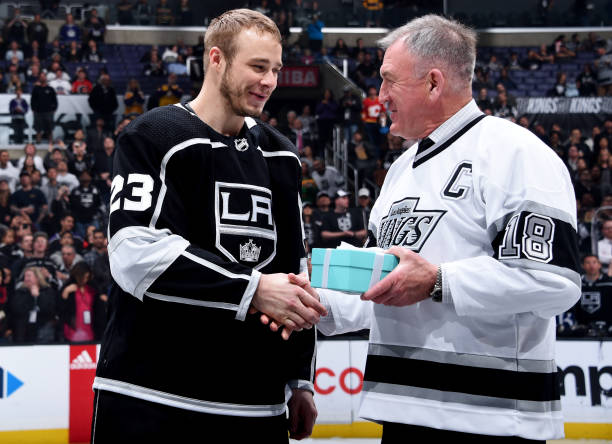Dustin Brown of the Los Angeles Kings and former Kings general manager and player Dave Taylor shake hands during a ceremony honoring Brown for...