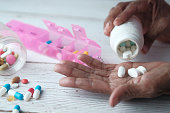 Elderly woman pouring pills from bottle on hand, top view