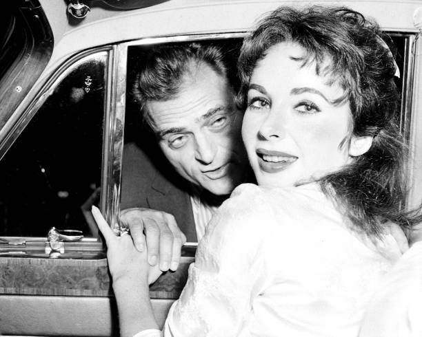 Elizabeth Taylor smiles happily on leaving Columbia Presbyterian Hospital as husband, Michael Todd holds her hand before joining her in car....
