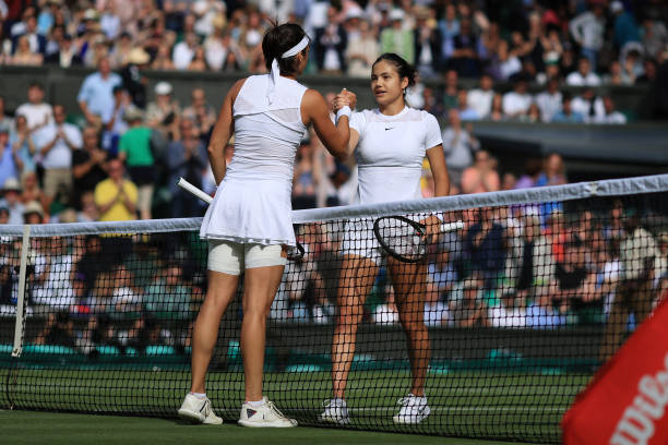 Emma Raducanu shakes hands with Caroline Garcia after their Ladies' Singles 2nd Round match during day three of The Championships Wimbledon 2022 at...