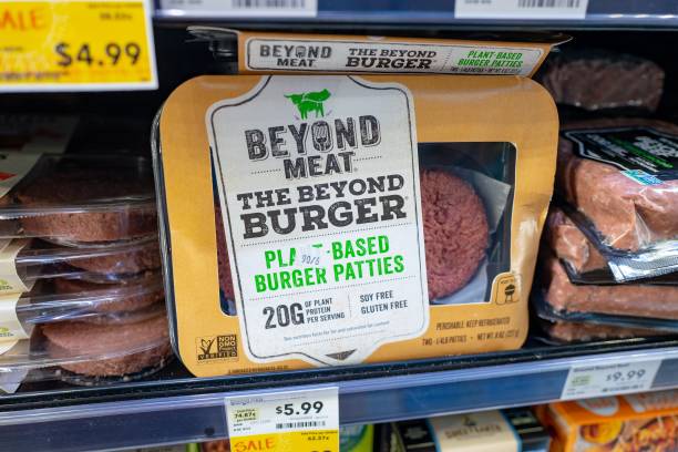 Engineered plant-based burger patties from food company Beyond Meat are visible on shelves among other meat alternatives at a grocery store in San...