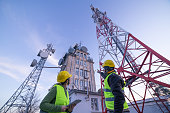 Engineers working on the field near a Telecommunications tower. Teamwork.