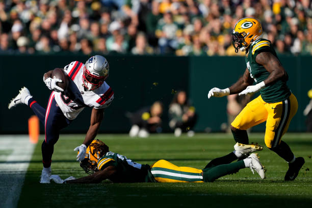 Eric Stokes of the Green Bay Packers knocks Damien Harris of the New England Patriots out of bounds during the first quarter at Lambeau Field on...