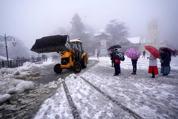 Excavator machine clears the snow from Ridge during heavy snowfall in on January 9, 2022 in Shimla, India.