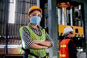 Factory woman worker or technician with hygienic mask stand with confident action with her co-worker  as background
