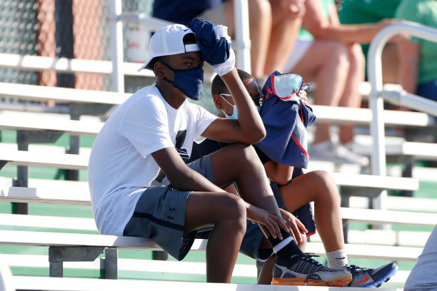 Fans wearing masks watch the action from the stands during the game between the Cathedral Fighting Irish and the Westfield Shamrocks on August 21,...