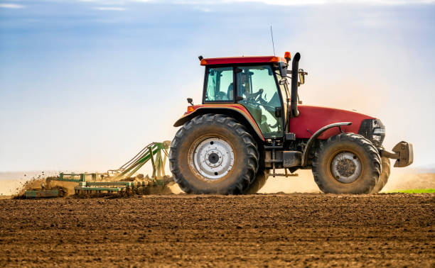 farmer in tractor plowing field in spring picture