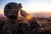 Female Army Solider Saluting against sunset sky