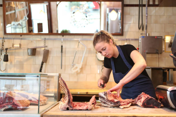 female butcher cutting meat in a butchers shop picture