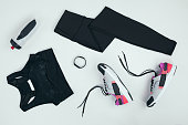 flat lay with sportswear with sneakers, fitness tracker and sports bottle isolated on grey
