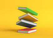 Flying color books on pastel yellow background