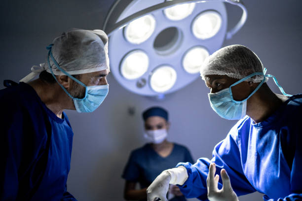 cirurgiões focados trabalhando juntos em uma cirurgia - plásticas - fotografias e filmes do acervo