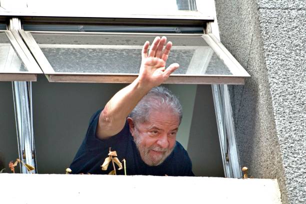 Former Brazilian President Luiz Inacio Lula da Silva waves at supporters from a window of the Workers Party state headquarters in Sao Paulo Brazil on...