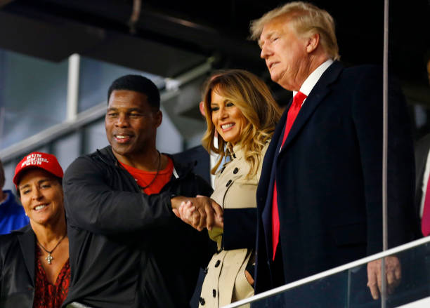 Former football player and political candidate Herschel Walker interacts with former president of the United States Donald Trump prior to Game Four...
