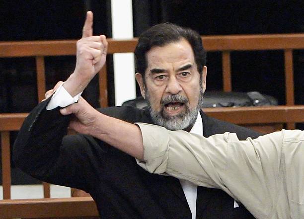 Former Iraqi President Saddam Hussein is held by a court bailiff during his trial in the fortified 'green zone', on November 5, 2006 in Baghdad,...