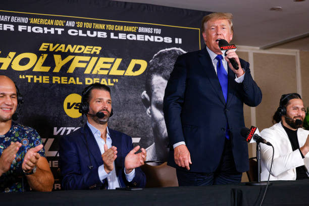 Former US President Donald Trump and Donald Trump Jr speak after the fight between Evander Holyfield and Vitor Belfort during Evander Holyfield vs....