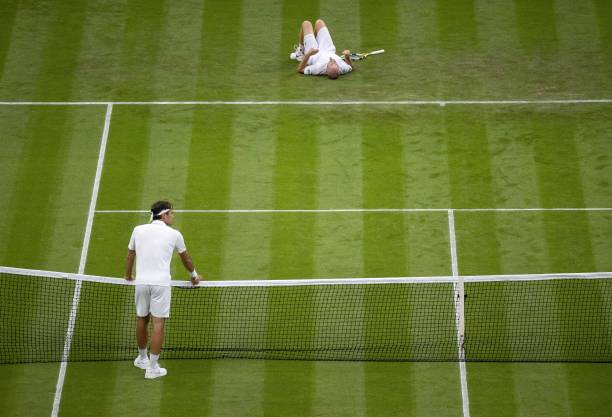 France's Adrian Mannarino lays on the court in jured after slipping while returning against Switzerland's Roger Federer during their men's singles...