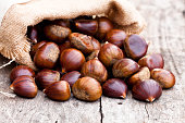 fresh  chestnuts in sack bag on the old wooden table