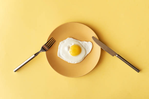 fried egg on yellow background, top view - egg stock pictures, royalty-free photos & images