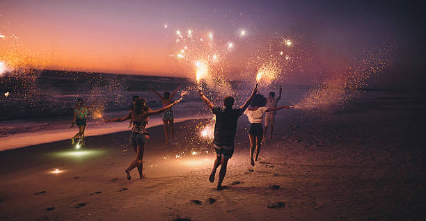 friends running with fireworks on a beach after sunset - freedom stock pictures, royalty-free photos & images