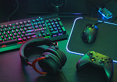 gamer work space concept, top view a gaming gear, mouse, keyboard, joystick, headset, mobile joystick, in ear headphone and mouse pad on black table background.