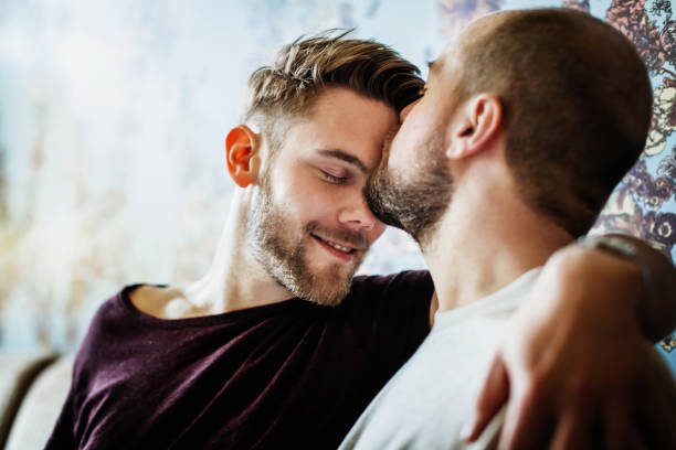 gay man kissing his partner on the head - love stock pictures, royalty-free photos & images