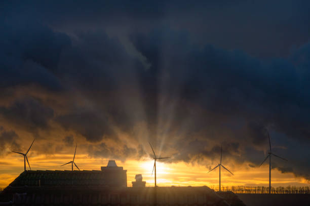 Germany, North Rhine-Westphalia, Grevenbroich, Storm clouds over wind farm at sunrise