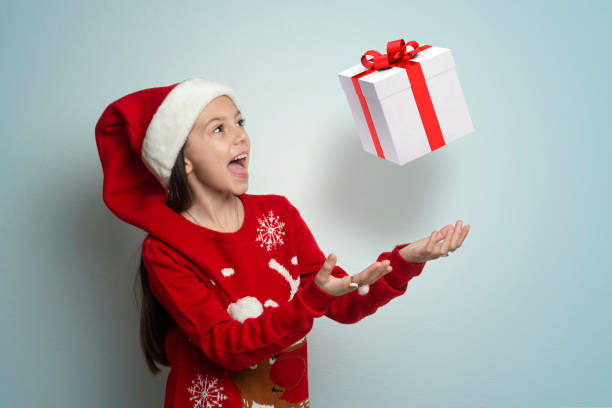 Girl In Santa Hat throws a Christmas present in the air