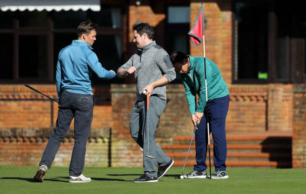 Golfers touch elbows instead of shaking hands as they play at Pine Ridge Golf Club on March 22, 2020 in Camberley, England. Coronavirus has spread to...