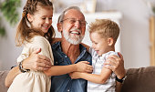 Grandfather hugging grandchildren on sofa