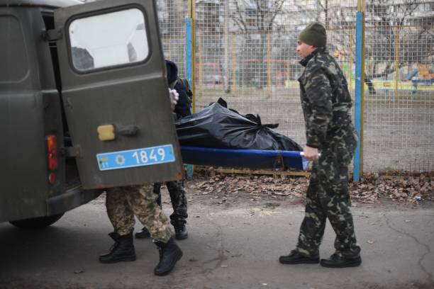 Graphic content / Ukrainian servicemen pick up the body of an Ukrainian man who was shot when a Russian armoured vehicle drove past him, on a...