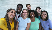 Group multiracial friends having fun outdoor - Happy mixed race people taking selfie together - Youth millennial generation and multi ethnic teenagers lifestyle concept