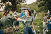 Group of volunteers with surgical masks cleaning nature together