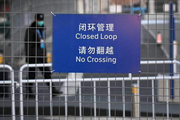 Guard is seen behind fences delineating the closed-loop bubble' set up by China as a preventative measure against the Covid-19 coronavirus, ahead of...