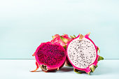 Half red and white dragon fruit on color background