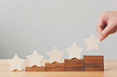 Hand putting wooden five star shape on table. The best excellent business services rating customer experience concept