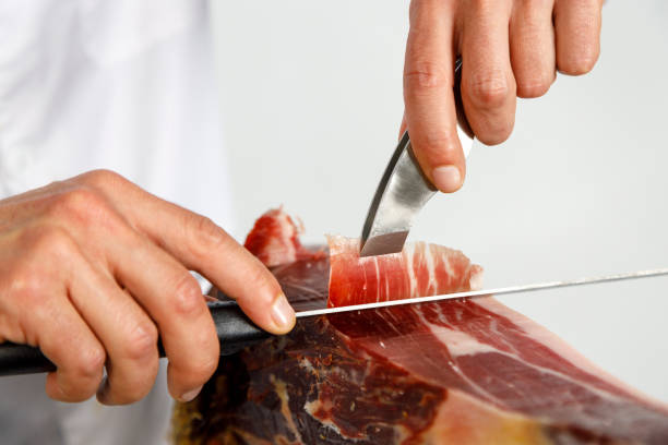 hands of male butcher cutting iberian ham at shop picture