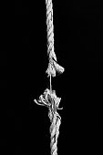 Hanging rope, frayed to its last strand, about to snap
