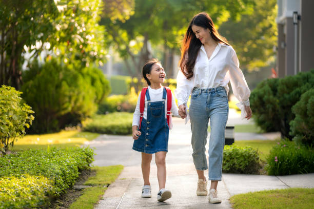 happy asian mother and daughter preschool student walking to school. beginning of lessons. first day of fall. parenthood or love and bonding expression concept. - asian mother and little daughter stock pictures, royalty-free photos & images
