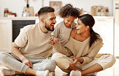 happy multiethnic family mom, dad and child  laughing, playing and tickles    on floor in cozy kitchen at home