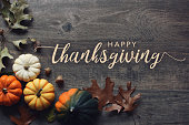 Happy Thanksgiving day greeting text with pumpkins, squash and leaves over dark wood table background