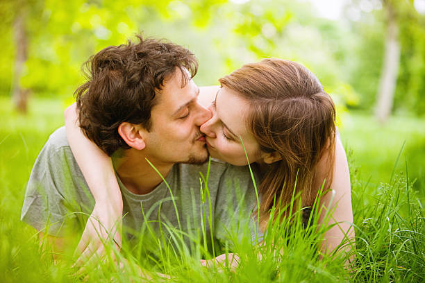 casal jovem feliz beijando na grama - saúde e vitalidade - fotografias e filmes do acervo