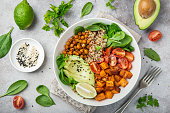 healhty vegan lunch bowl. Avocado, quinoa, sweet potato, tomato, spinach and chickpeas vegetables salad