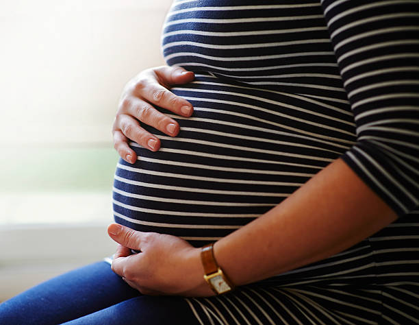 امرأة حامل بشدة تحمل نتوءها - مخزون صور للنساء الحوامل ، صور خالية من حقوق الملكية