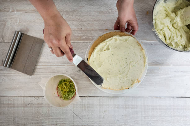 high angle view of a person smoothing buttercream icing over a fresh baked gin and tonic flavoured cake. - frosting a cake stock pictures, royalty-free photos & images