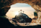 High resolution. Easter Sunday concept: Empty tomb stone with cross on meadow sunrise background. 3d rendering