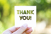 Holding the paper with Thank You message in front of a beautiful blur nature background